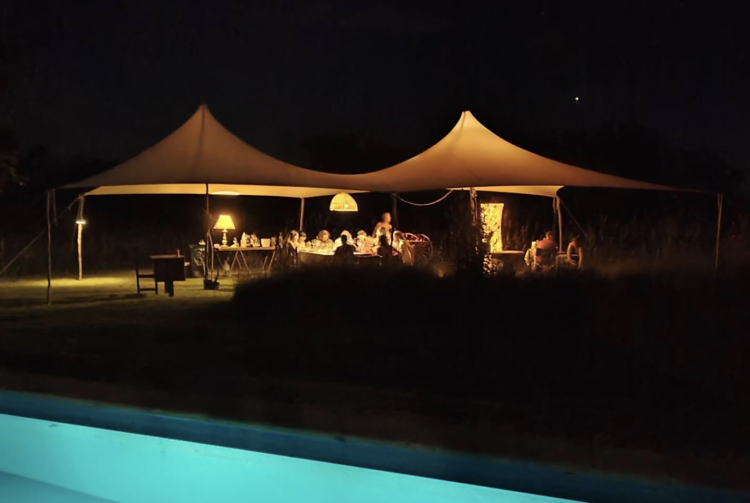 La carpa de Beleza iluminada junto a la pileta